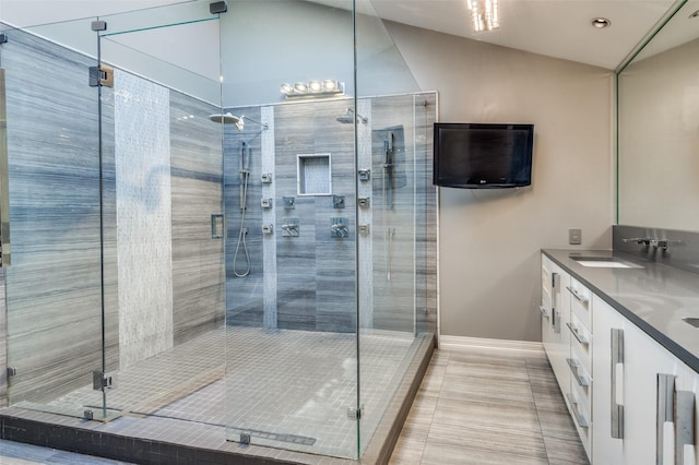 bathroom with a shower with door, vanity, lofted ceiling, and tile patterned flooring