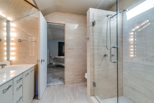 bathroom with vanity, an enclosed shower, vaulted ceiling, and tile walls