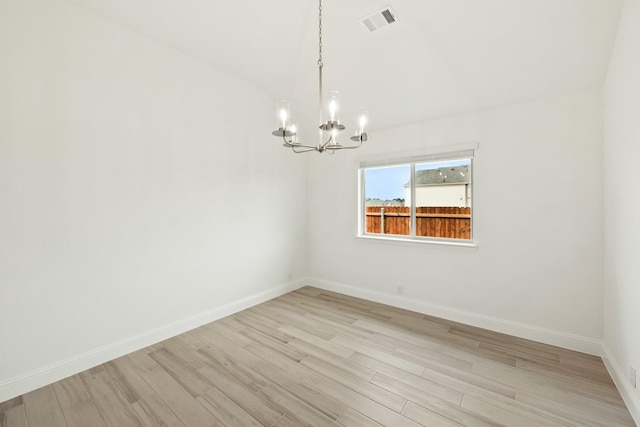 empty room featuring a chandelier, light wood-type flooring, visible vents, and baseboards