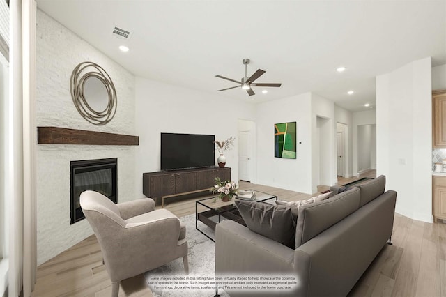 living area featuring visible vents, a ceiling fan, light wood-style flooring, a stone fireplace, and recessed lighting