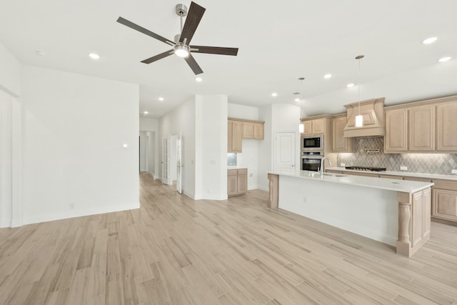 kitchen featuring stainless steel appliances, open floor plan, light countertops, tasteful backsplash, and custom range hood