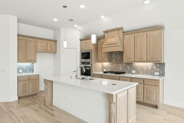 kitchen featuring lofted ceiling, sink, light wood-type flooring, an island with sink, and stainless steel appliances