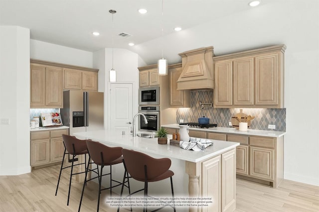 kitchen with light countertops, appliances with stainless steel finishes, a kitchen bar, and custom range hood