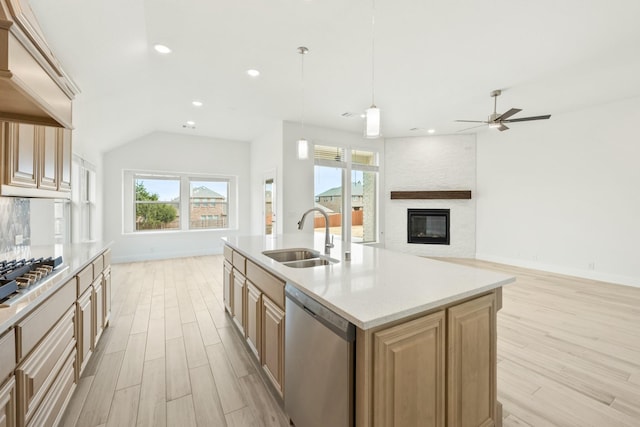 kitchen featuring a fireplace, a center island with sink, appliances with stainless steel finishes, light wood-style floors, and a sink