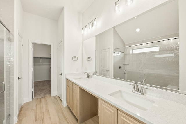 full bath with double vanity, a sink, a shower stall, and wood finished floors