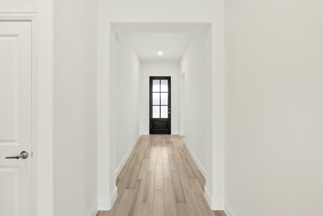 corridor featuring light wood finished floors and baseboards