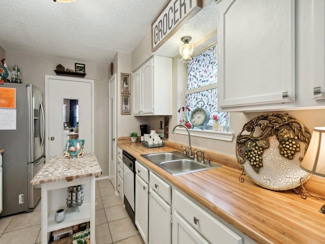 kitchen with light tile patterned floors, white cabinets, dishwashing machine, stainless steel refrigerator with ice dispenser, and a sink