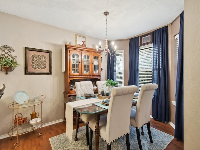 dining room featuring a chandelier, a textured ceiling, baseboards, and wood finished floors