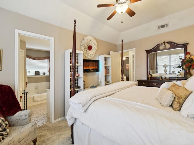 bedroom featuring multiple windows, lofted ceiling, light colored carpet, and ensuite bath