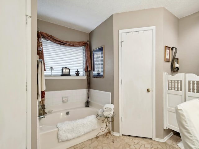 bathroom with a textured ceiling and a tub to relax in