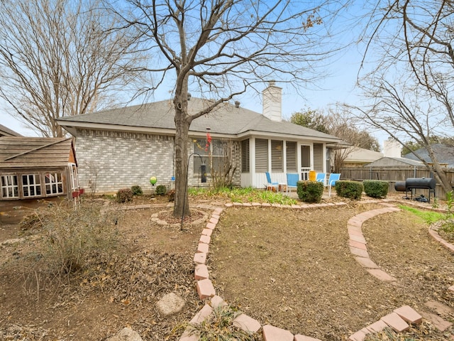 exterior space with brick siding, a chimney, and fence