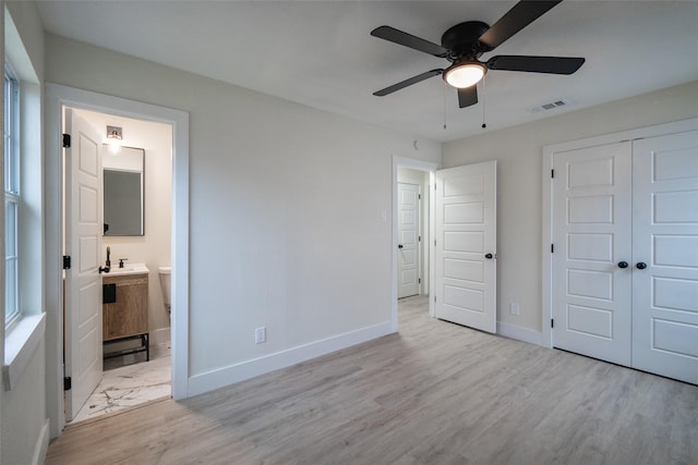 unfurnished bedroom with sink, light hardwood / wood-style flooring, ceiling fan, ensuite bath, and a closet