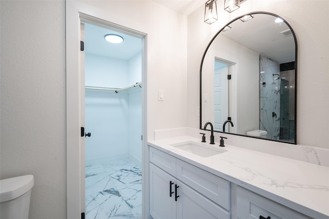 bathroom with a shower with door, vanity, and toilet