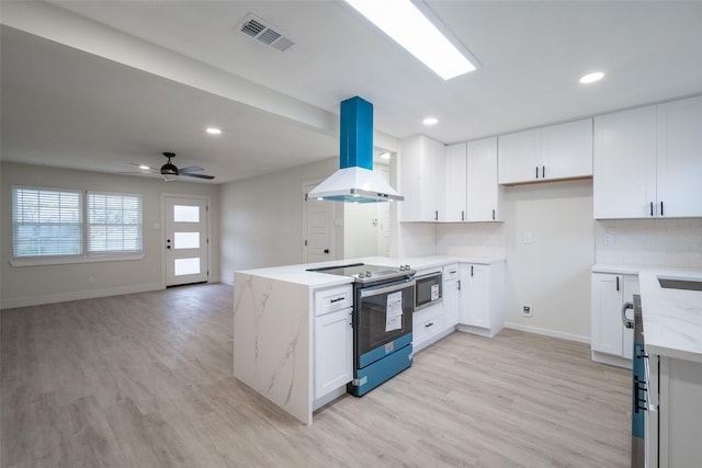 kitchen with white cabinetry, island range hood, stainless steel appliances, light stone countertops, and decorative backsplash