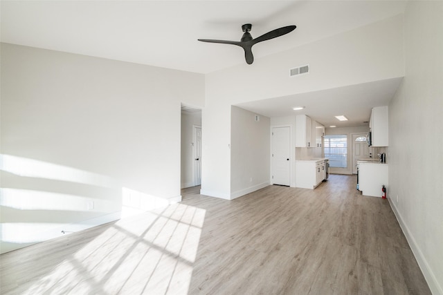 unfurnished living room with vaulted ceiling, ceiling fan, and light wood-type flooring