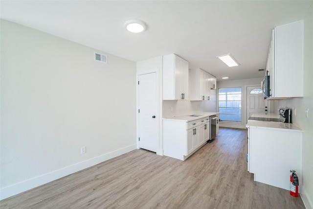 kitchen with white cabinetry, light wood-type flooring, and appliances with stainless steel finishes