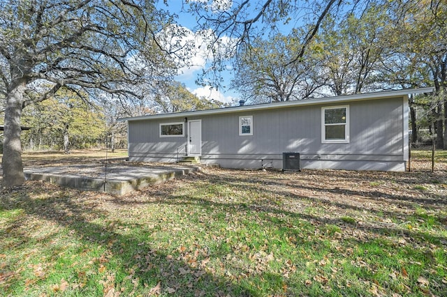 rear view of property with a lawn and central air condition unit