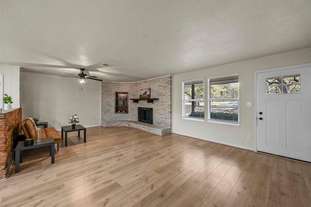 living room with ceiling fan, a fireplace, and light hardwood / wood-style floors