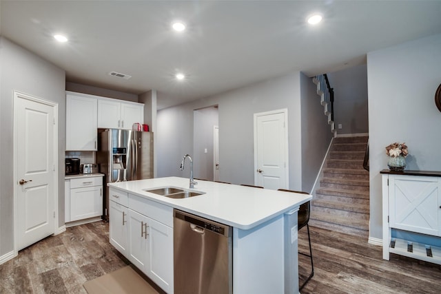 kitchen with stainless steel appliances, an island with sink, sink, and white cabinets