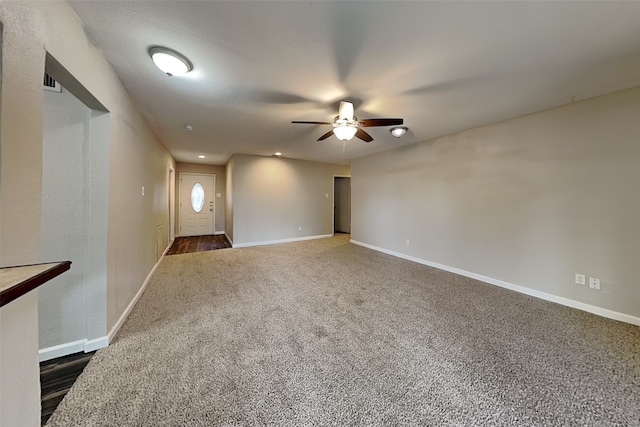 empty room with ceiling fan and dark colored carpet