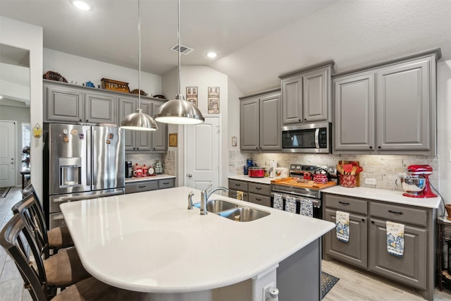 kitchen with visible vents, gray cabinets, a sink, backsplash, and appliances with stainless steel finishes