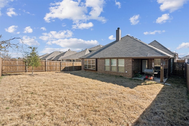 back of house featuring brick siding, a fenced backyard, a patio area, and a yard