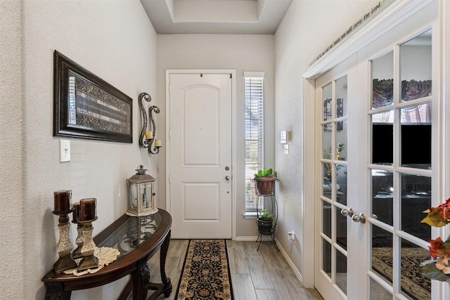 foyer entrance featuring light wood-style flooring, french doors, and baseboards