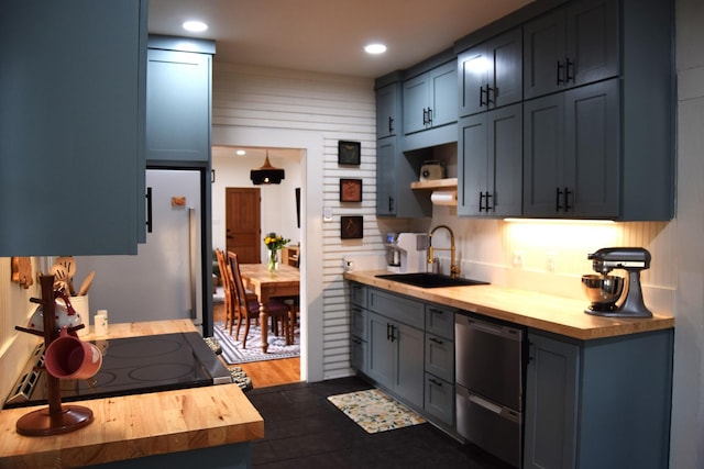 kitchen featuring dishwasher, range with electric cooktop, sink, and wood counters