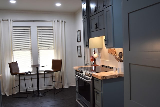 kitchen featuring crown molding, blue cabinetry, wooden counters, and stainless steel electric range