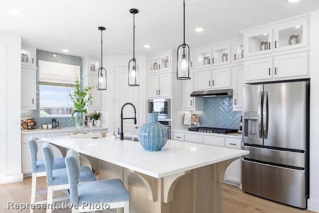 kitchen featuring white cabinetry, stainless steel appliances, and a center island with sink