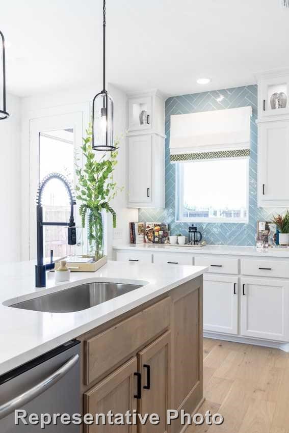 kitchen with sink, tasteful backsplash, decorative light fixtures, dishwasher, and white cabinets