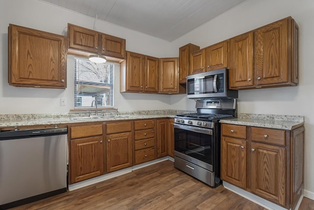 kitchen featuring dark hardwood / wood-style flooring, sink, light stone counters, and stainless steel appliances