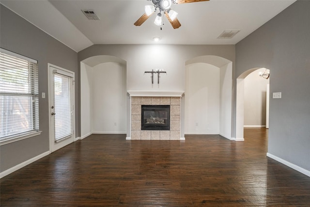 unfurnished living room with a tiled fireplace, lofted ceiling, dark hardwood / wood-style floors, and ceiling fan