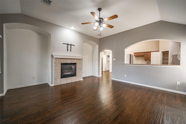 unfurnished living room featuring dark wood-type flooring, ceiling fan, lofted ceiling, and a tile fireplace