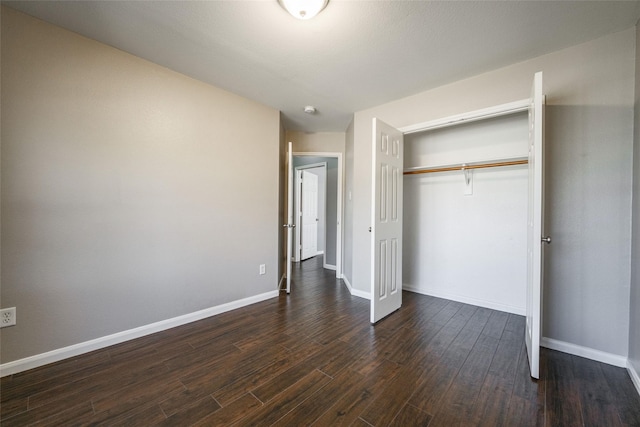 unfurnished bedroom with dark hardwood / wood-style flooring and a closet