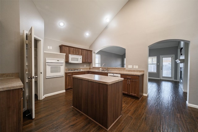 kitchen featuring sink, white appliances, high vaulted ceiling, a kitchen island, and dark hardwood / wood-style flooring