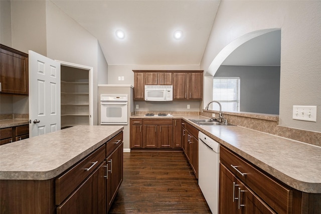 kitchen featuring sink, vaulted ceiling, dark hardwood / wood-style floors, kitchen peninsula, and white appliances