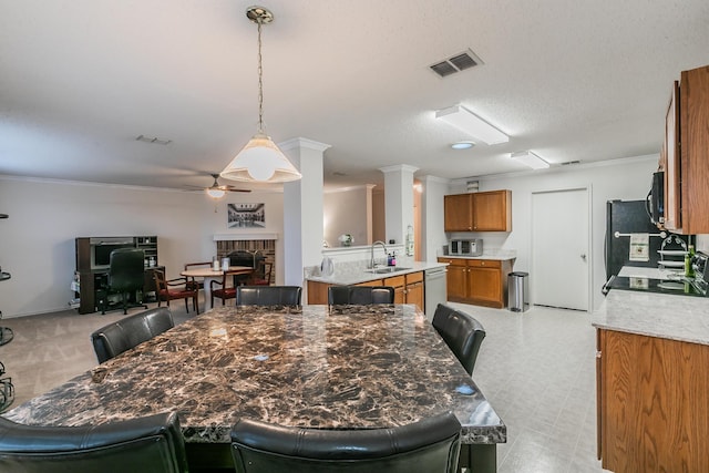 dining room featuring sink, crown molding, a textured ceiling, ceiling fan, and decorative columns