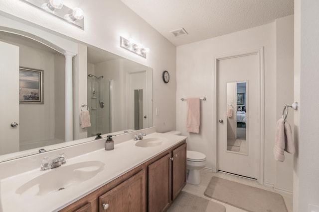 bathroom with a shower with shower door, decorative columns, vanity, toilet, and a textured ceiling