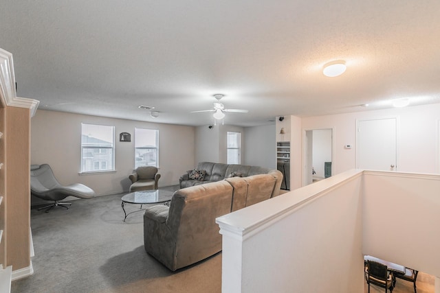 living room with ceiling fan, carpet flooring, and a textured ceiling