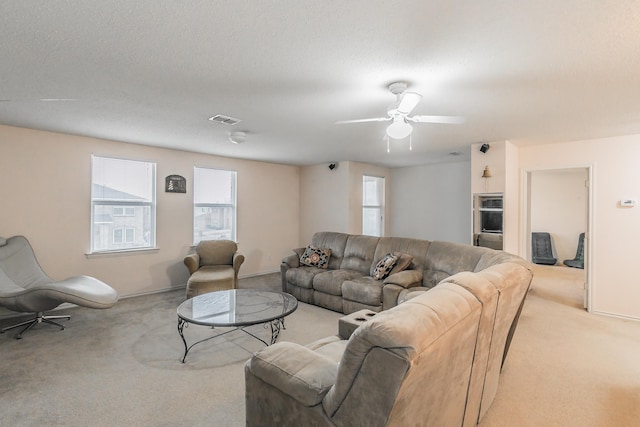 carpeted living room featuring ceiling fan and a textured ceiling