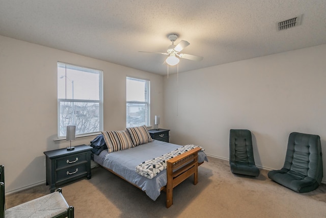 bedroom with ceiling fan, light carpet, and a textured ceiling