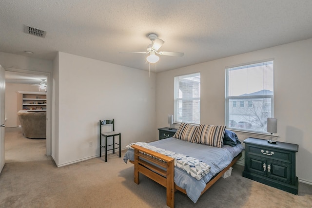 bedroom featuring ceiling fan, light carpet, and a textured ceiling