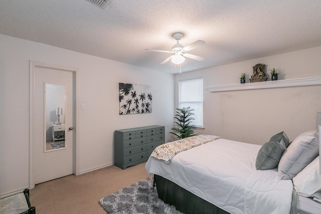 bedroom featuring ceiling fan, light colored carpet, and a textured ceiling