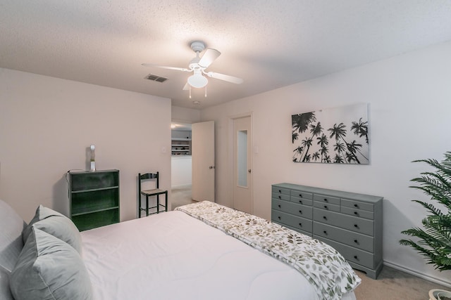 bedroom with ceiling fan, carpet floors, and a textured ceiling