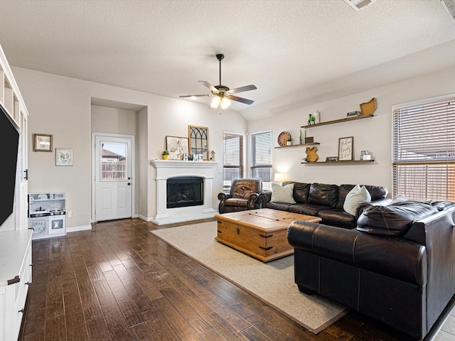 living room featuring ceiling fan, dark hardwood / wood-style floors, vaulted ceiling, and a textured ceiling