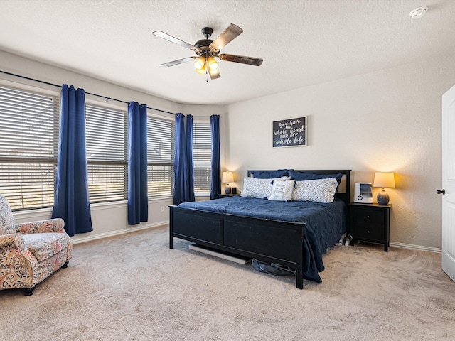 bedroom with ceiling fan, light colored carpet, and a textured ceiling