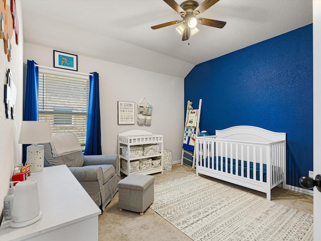 bedroom with a nursery area, lofted ceiling, carpet flooring, and ceiling fan