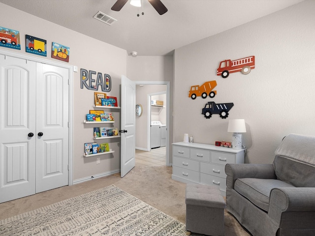 sitting room featuring light carpet, washer and clothes dryer, and ceiling fan