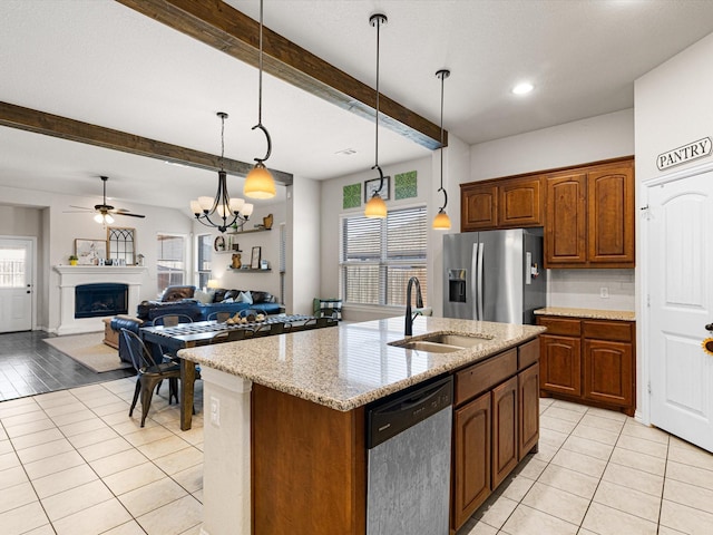 kitchen with sink, appliances with stainless steel finishes, an island with sink, pendant lighting, and beam ceiling